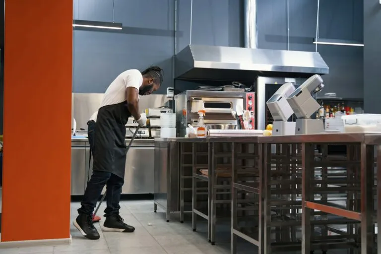 Adult chef cleaning kitchen workspace in restaurant, emphasizing hygiene and organization for optimal food service and dining comfort.