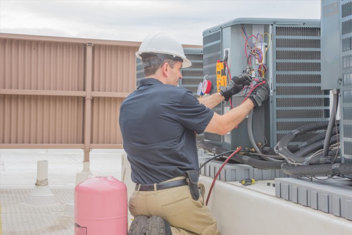 HVAC technician performing maintenance on commercial air conditioning unit on rooftop, highlighting the importance of professional HVAC services in Dallas, TX.
