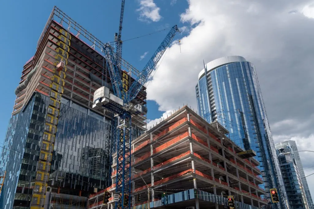 Skyscraper construction site featuring a crane, scaffolding, and modern glass buildings, symbolizing new commercial development and HVAC system installations by Proactive Air Conditioning.
