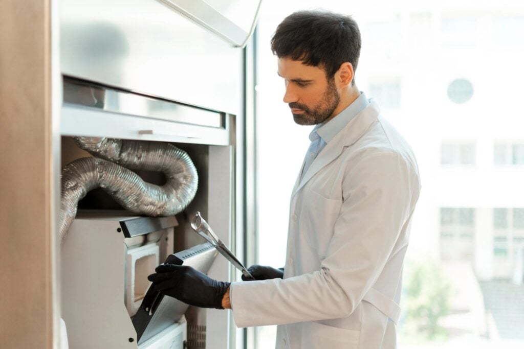 Technician in lab coat using tools to inspect HVAC system, emphasizing furnace maintenance for efficiency and safety in Dallas homes.