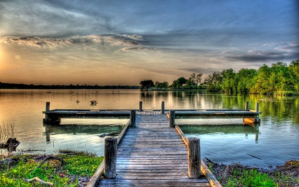 Scenic lake view from a wooden dock. Calm water reflects the sky and trees. Ideal for relaxation, Heat Pump Maintenance in Dallas, TX.