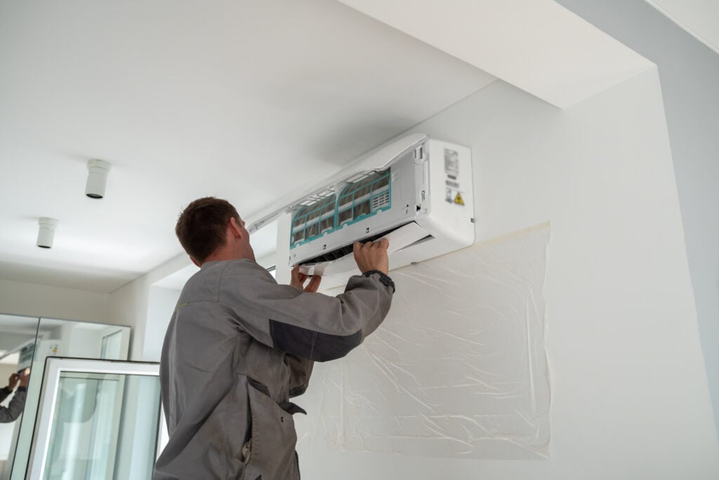 Male technician installing a ductless mini-split air conditioning unit on a wall in a residential setting, emphasizing professional installation services by Proactive Air Conditioning in Dallas, TX.