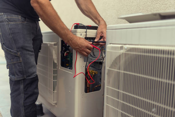 HVAC technician in Dallas, TX, servicing ductless heating system, ensuring efficient and reliable climate control, using testing equipment.