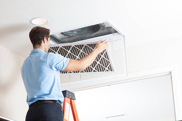 Man removing air filter from ceiling vent during air duct cleaning service in Dallas, TX, emphasizing HVAC maintenance and improved indoor air quality.