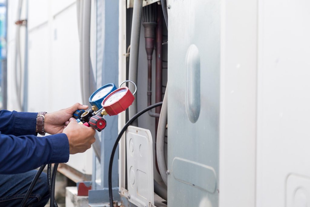 Technician using pressure gauges on HVAC system for heating repair and maintenance in Dallas.