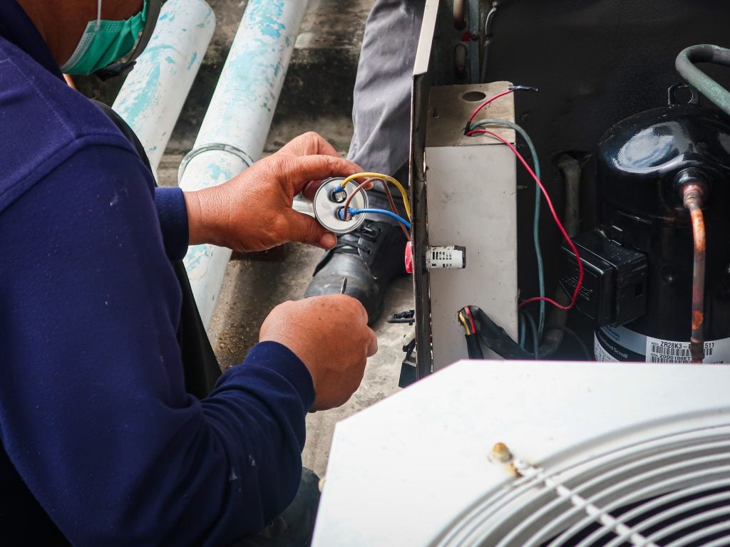 Heat pump installation being done by a technician. This is a heat pump replacement process to ensure efficient heating and cooling systems.