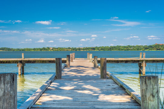 Scenic lake view with wooden pier under a blue sky, ideal for a relaxing getaway. Consider  for your next escape. Dallas, TX