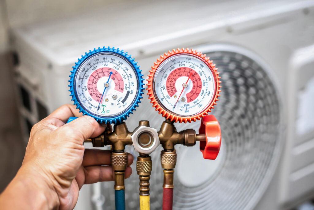 Hand holding HVAC gauges for air conditioning diagnostics, with a background of an outdoor unit, illustrating Proactive Air Conditioning's expert service in Oak Lawn, Dallas.