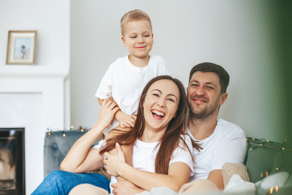 Happy young family with a child sitting together on a couch, representing comfort and reliability in home life, relevant to HVAC services for Oak Lawn residents.