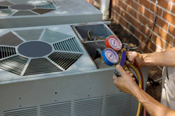 HVAC technician using pressure gauges on air conditioning unit for maintenance and repair services in Bluffview, Dallas.