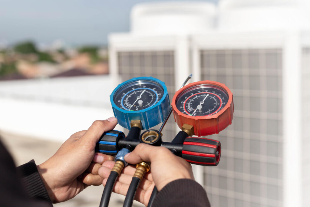 Close-up of technician hands holding HVAC manifold gauges to check pressure on a rooftop unit for the Belmont Addition project